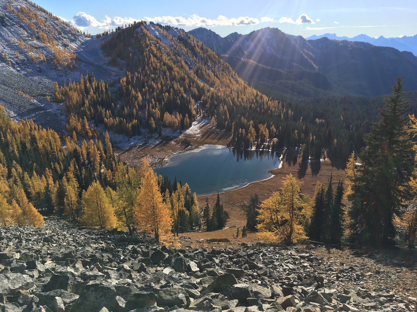 A photo of a lake in a valley ringed by snowy mountains.